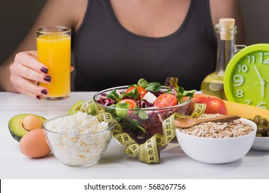 Woman On A Diet. Healthy And Proper Food With Salad And Dairy Product On Wooden Table. Glass Of Juice In Hand.