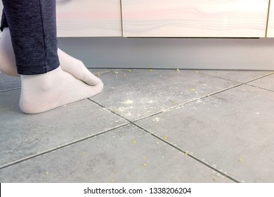 Woman On The Dirty Floor In The Kitchen. Leftovers And Crumbs On The Kitchen Floor. Legs Close-up