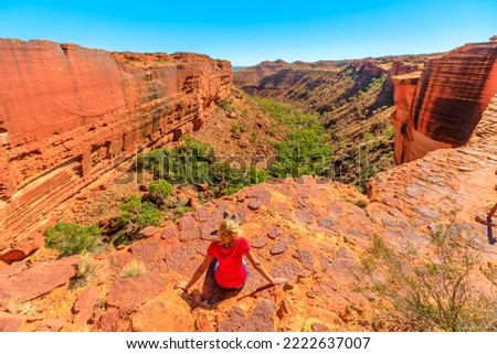 woman on the edge of Kings Canyon in Watarrka National Park, Australia's Red Center. rest after trekking on Rim Walk by the canyon edge in Northern Territory of Australian Outback.