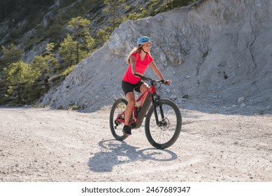 Woman on an electric mountain bike going downhill on a rough rocky terrain. Summer, sport, and adventure concepts. - Powered by Shutterstock