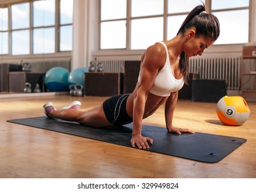 Woman on fitness mat doing stretching exercises at gym. Fit caucasian woman working out at health club.