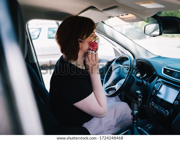 Woman\
on her way to work is putting on a face mask in\
car