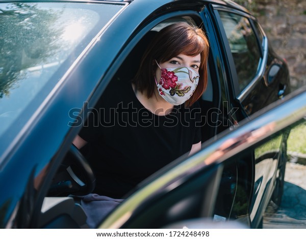 Woman
on her way to work is putting on a face mask in
car