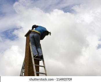 Woman On A High Extension Ladder Cleaning A Brick Chimney