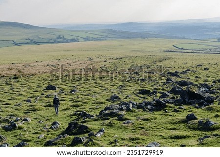 A woman on a hike decends from a tor on Dartmoor National Park in Devon, England in the UK