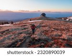 Woman on hiking trail from mountain hut Wolfsbergerhuette (Wolfsberger Huette) during sunrise on Saualpe, Lavanttal Alps, Carinthia, Austria, Europe. Remote cottage with panoramic view on Wolfsberg