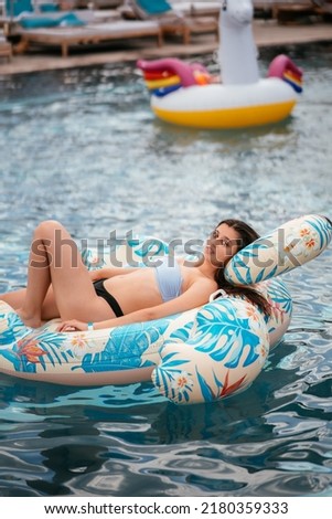 Woman on inflatable Flamingo floating in swimming pool.
