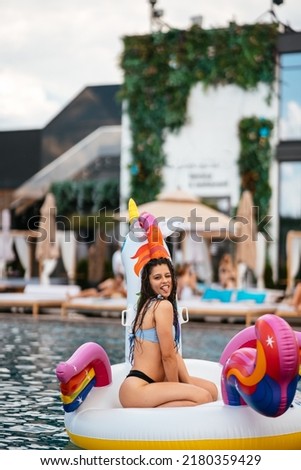 Woman on inflatable unicorn toy mattress float in pool.