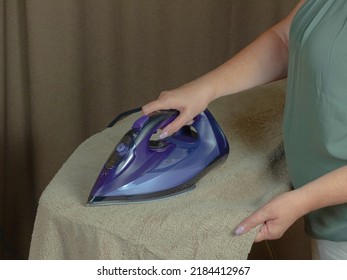 Woman On Ironing Board Ironing A Large Terry Towel