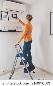 Woman the ladder hanging pictures   photos the shelf   wall at home 