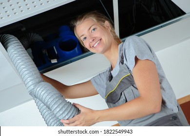 Woman On A Ladder Working With Ventilation Pipes