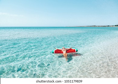 Woman on lilo in the sea water. Girl relaxing on inflatable ring on the beach. Summer vacations, idyllic scene.