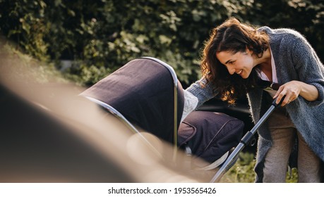Woman on maternity leave taking her baby out in a stroller. Woman with baby pram outdoors.