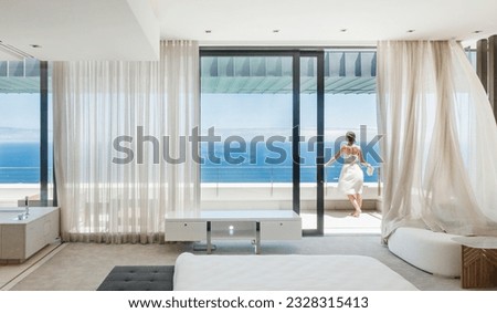 Woman on modern balcony overlooking ocean