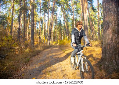 Woman on a mountain bike in the autumn forest on a bright sunny day