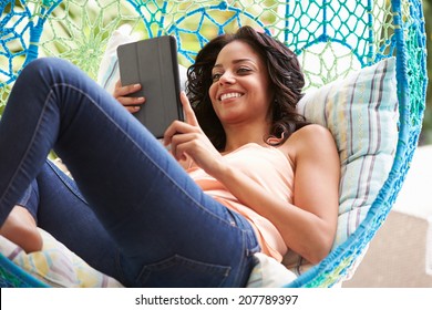 Woman On Outdoor Garden Swing Seat Using Digital Tablet - Powered by Shutterstock