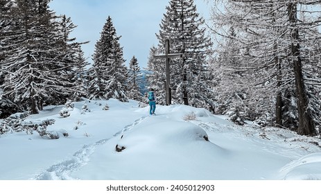 Woman on panoramic hiking trail on way to snow covered mountain peak Reinischkogel, Koralpe, Lavanttal Alps, Styria, Austria. Winter wonderland with snow covered tall pine trees in Austrian Alps - Powered by Shutterstock