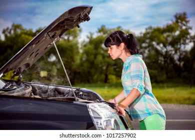 Woman on the road near the car. Damage to vehicle problems on the road.