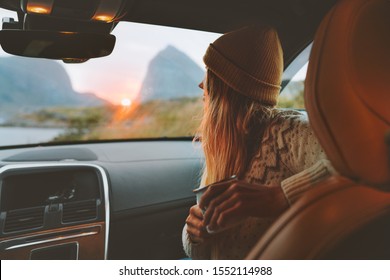 Woman on road trip traveling by rental car relaxing with coffee cup adventure lifestyle vacations vibes outdoor sunset Norway mountains view in window 
