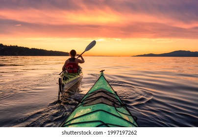 Woman on a sea kayak is paddling in the ocean. Colorful Sunset Sky Art Render. Taken in Jericho, Vancouver, British Columbia, Canada. - Powered by Shutterstock