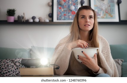 Woman On Sofa Watching Movie Using Digital LCD Video Projector, Home Theater