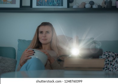 Woman On Sofa Watching Movie Using Digital LCD Video Projector, Home Theater