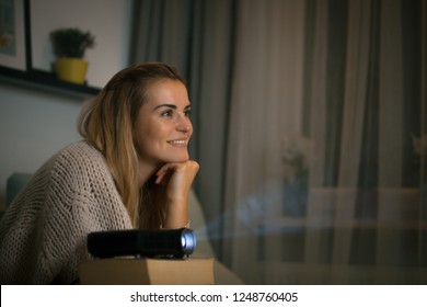 Woman On Sofa Watching Movie Using Digital LCD Video Projector, Home Theater