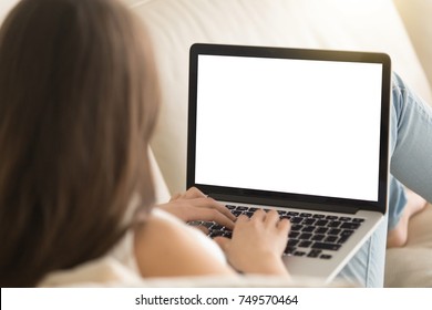 Woman on sofa working on laptop with mockup blank screen. Empty copyspace on monitor for  advertisement, language learning ad, online shopping website, social media site. Close up, focus on screen. - Shutterstock ID 749570464