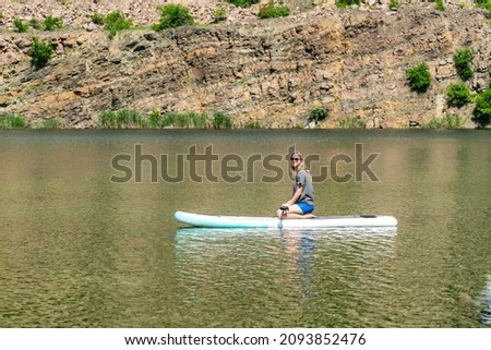 Woman on sup board with paddle in the lake