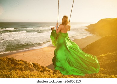 Woman On A Swing Above The Beach