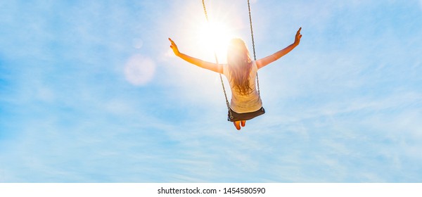 Woman on a swing with blue sky in the back light