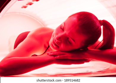 Woman On Tanning Bed. Attractive Young Woman Lying On Tanning Bed And Keeping Eyes Closed