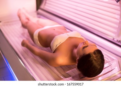 Woman On Tanning Bed. Top View Of Attractive Young Woman Lying On Tanning Bed