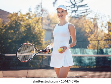 Woman On The Tennis Court In Proper Attire With Racket And Ball