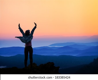 woman on top of the mountain looking to the sun