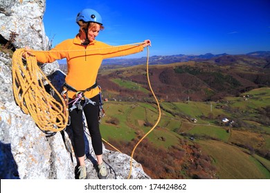 Woman on top of the route coils the rope for abseil  - Powered by Shutterstock