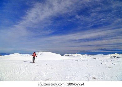 Woman on touring skis isolated on alpine plateau in sunny winter day