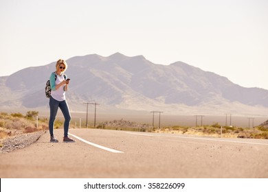 Woman On Vacation Hitchhiking Along Road Using Mobile Phone