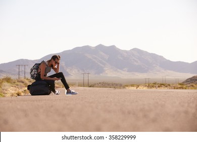 Woman On Vacation Hitchhiking Along Road Using Mobile Phone