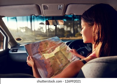 Woman on vacation looking at map for directions while driving in car