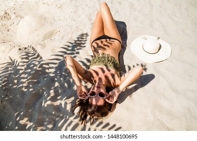 Woman On Vacation. Sunny Summer. All Inclusive Hotel. Trip To The Sea. Girl Sunbathes On The Sand. Shadow Of A Tropical Plant