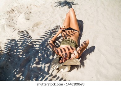 Woman On Vacation. Sunny Summer. All Inclusive Hotel. Trip To The Sea. Girl Sunbathes On The Sand. Shadow Of A Tropical Plant