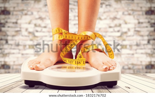 Woman on weight\
scales and measuring tape