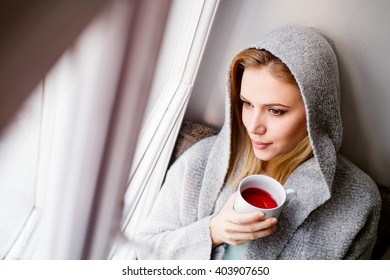 Woman On Window Sill Holding A Cup Of Tea