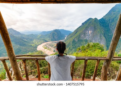 Woman on wooden balcony conquering mountain top at Nong Khiaw Nam Ou River valley Laos mature people traveling millenials concept travel destination in South East Asia - Shutterstock ID 1407515795