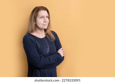 A woman on a yellow background looks up with hope, there are difficulties and problems in her life, but she is not disappointed, she believes and prays, she wants to be a good mother and wife - Shutterstock ID 2278333091