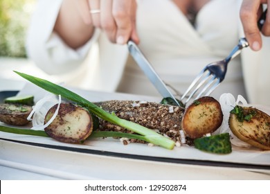 Woman In An Open Air Restaurant Preparing To Eat Fish And Potatoes