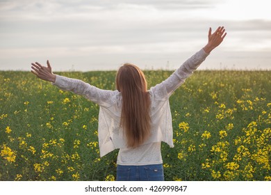 woman with open arms in the green wheat field at the morning.