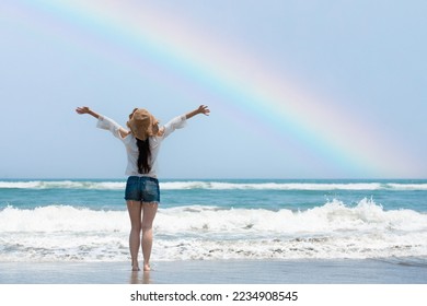 Woman open arms on rainbow beach