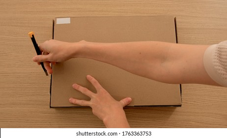 Woman open a box parcel in a box with clothes top view. Concept delivery and online shopping